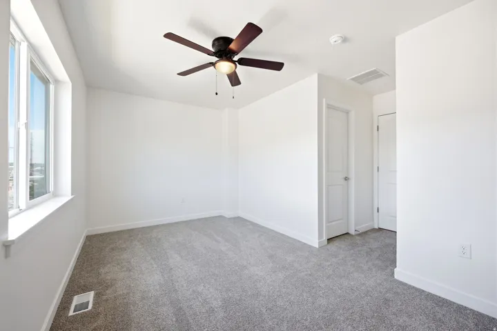 Carpeted room with a ceiling fan light fixture