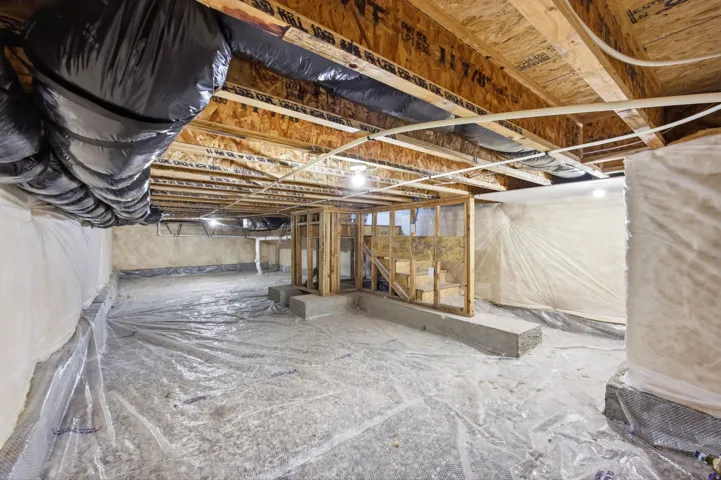 Crawl space with wood framing, exposed joists, and a vapor barrier covering the floor and walls