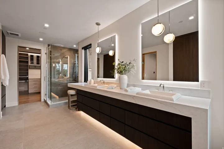 Modern bathroom featuring a dual vanity with vessel sinks, white stone countertops, and dark wood-finish cabinetry