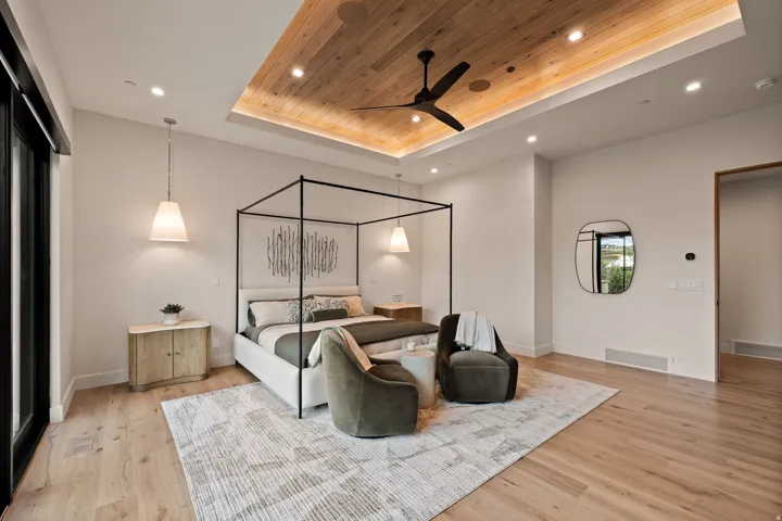 Spacious room featuring wood-finish flooring, a tray ceiling with recessed lighting and a ceiling fan, and a large glass door