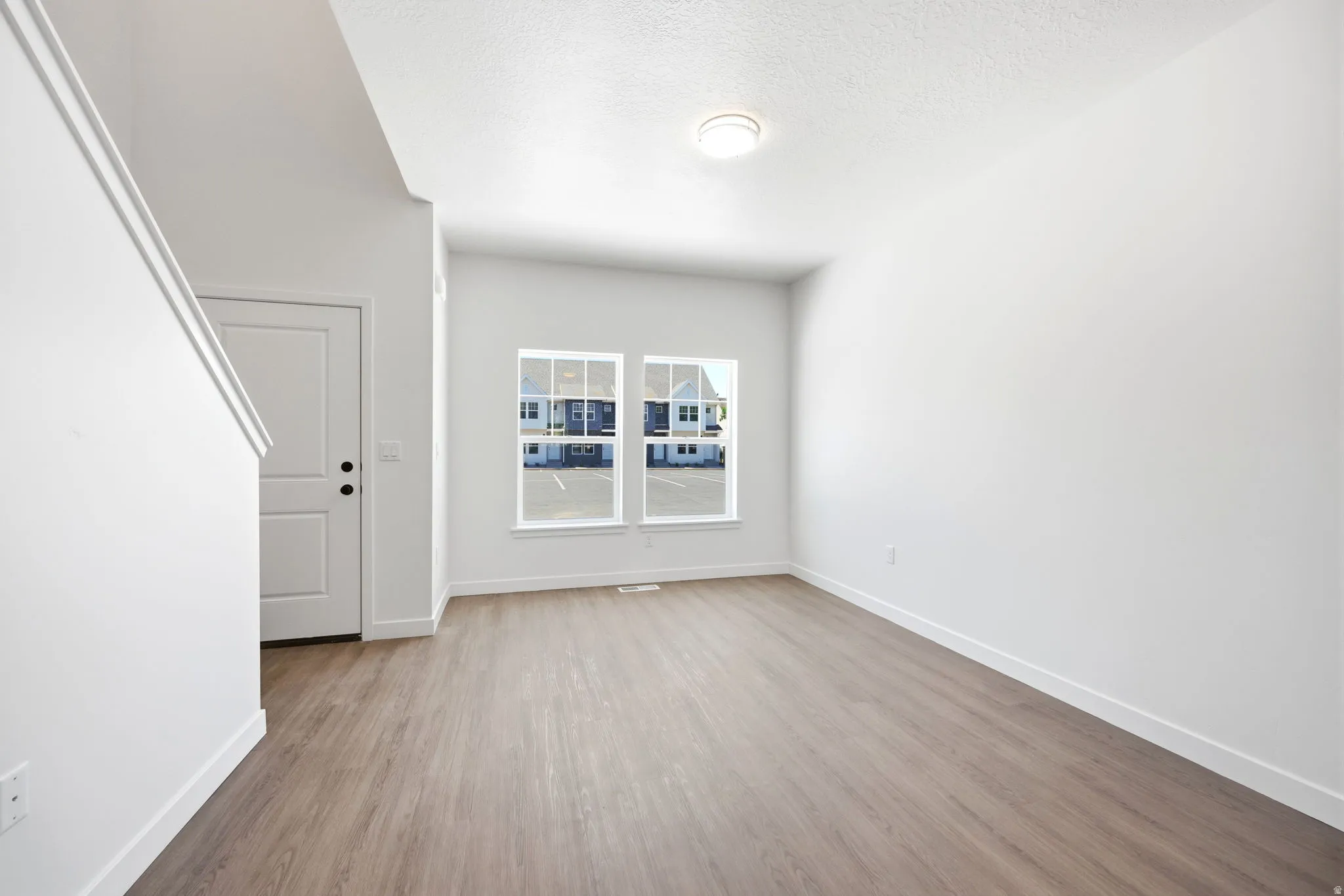 Bright interior space featuring wood-finish flooring, white trim, and a white paneled door