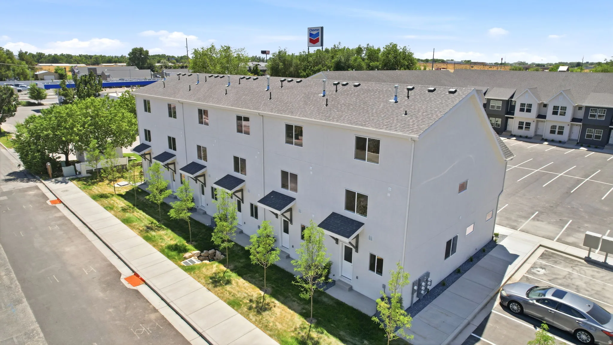 Newly constructed townhome-style building with a light-colored exterior, multiple windows, and individual covered entryways