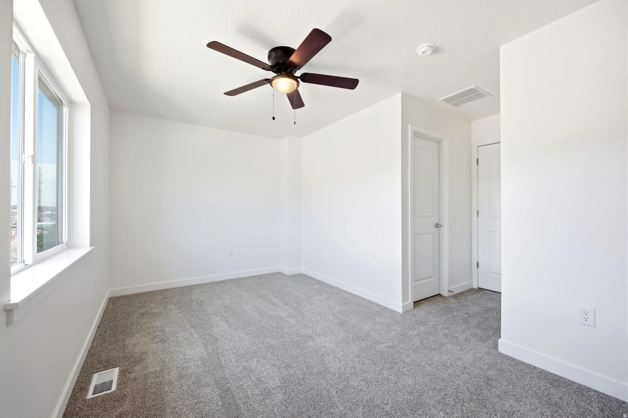 Carpeted room with a ceiling fan light fixture