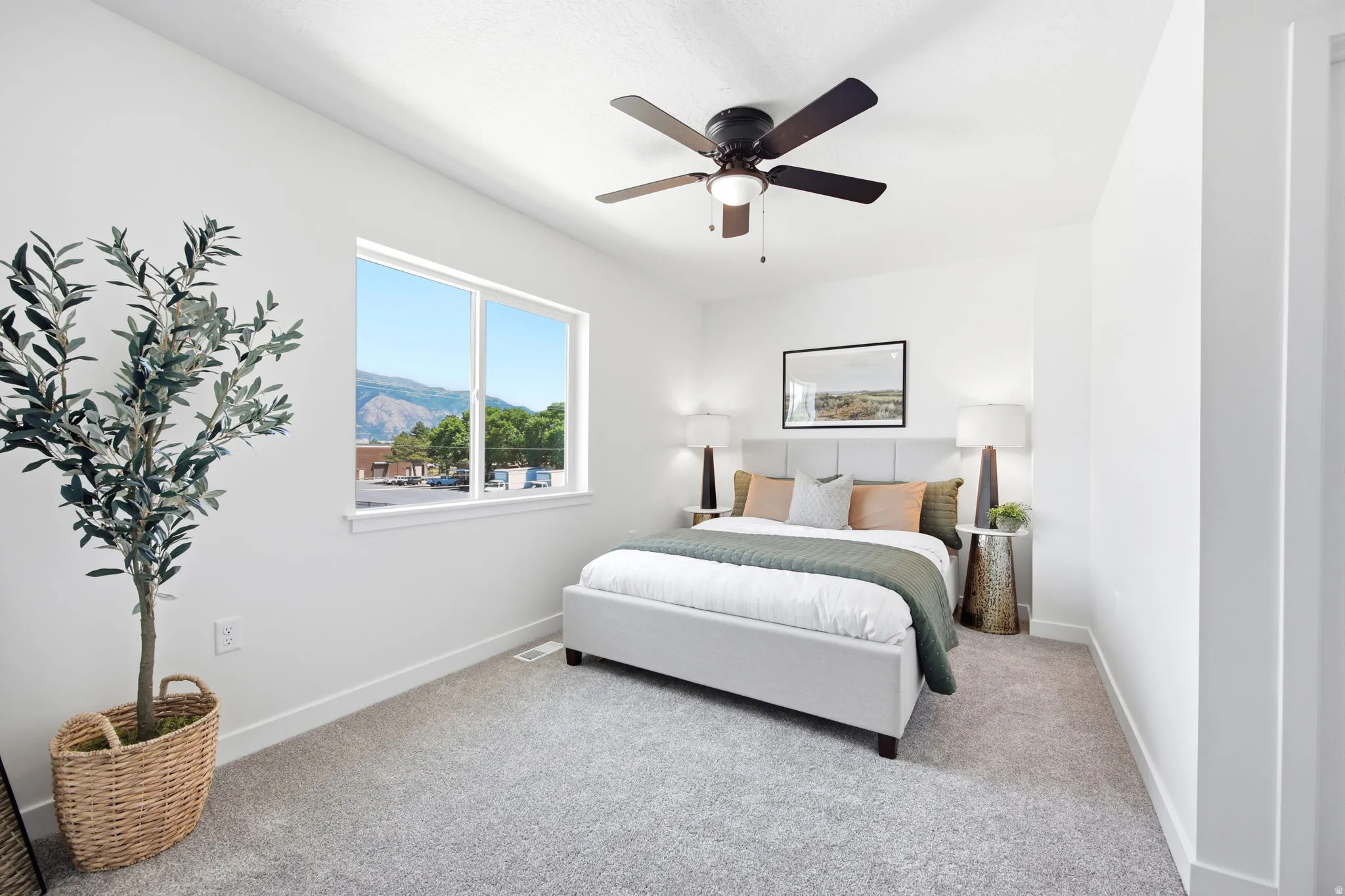 Bright room featuring a window with a mountain backdrop, a ceiling fan with integrated lighting, clean white walls, and gray carpeting