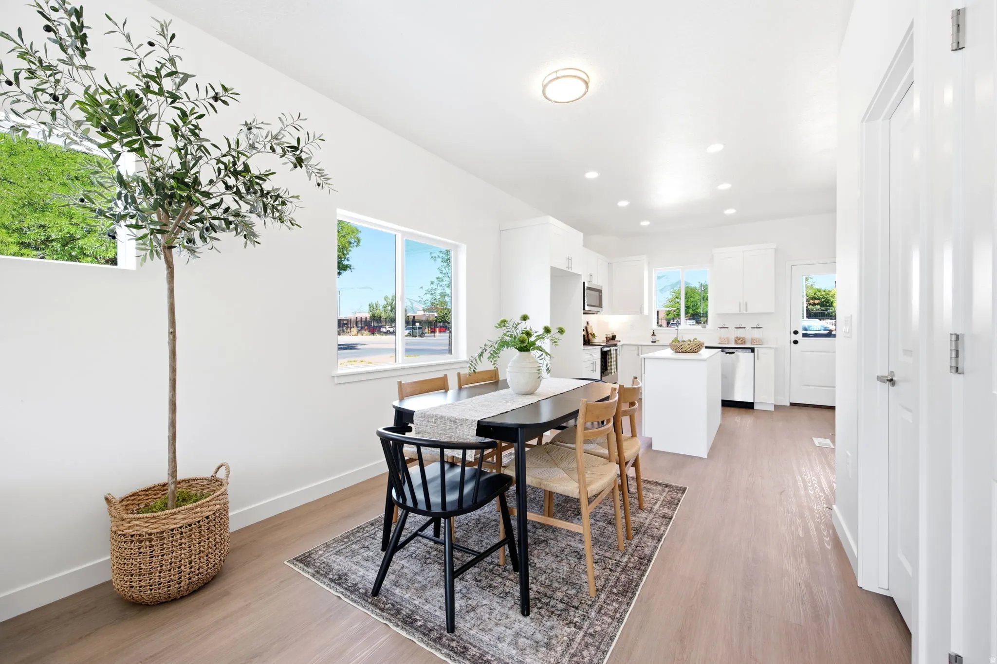 Open-concept dining area and kitchen featuring light wood-finish flooring, recessed lighting, white cabinetry, and a white kitchen island
