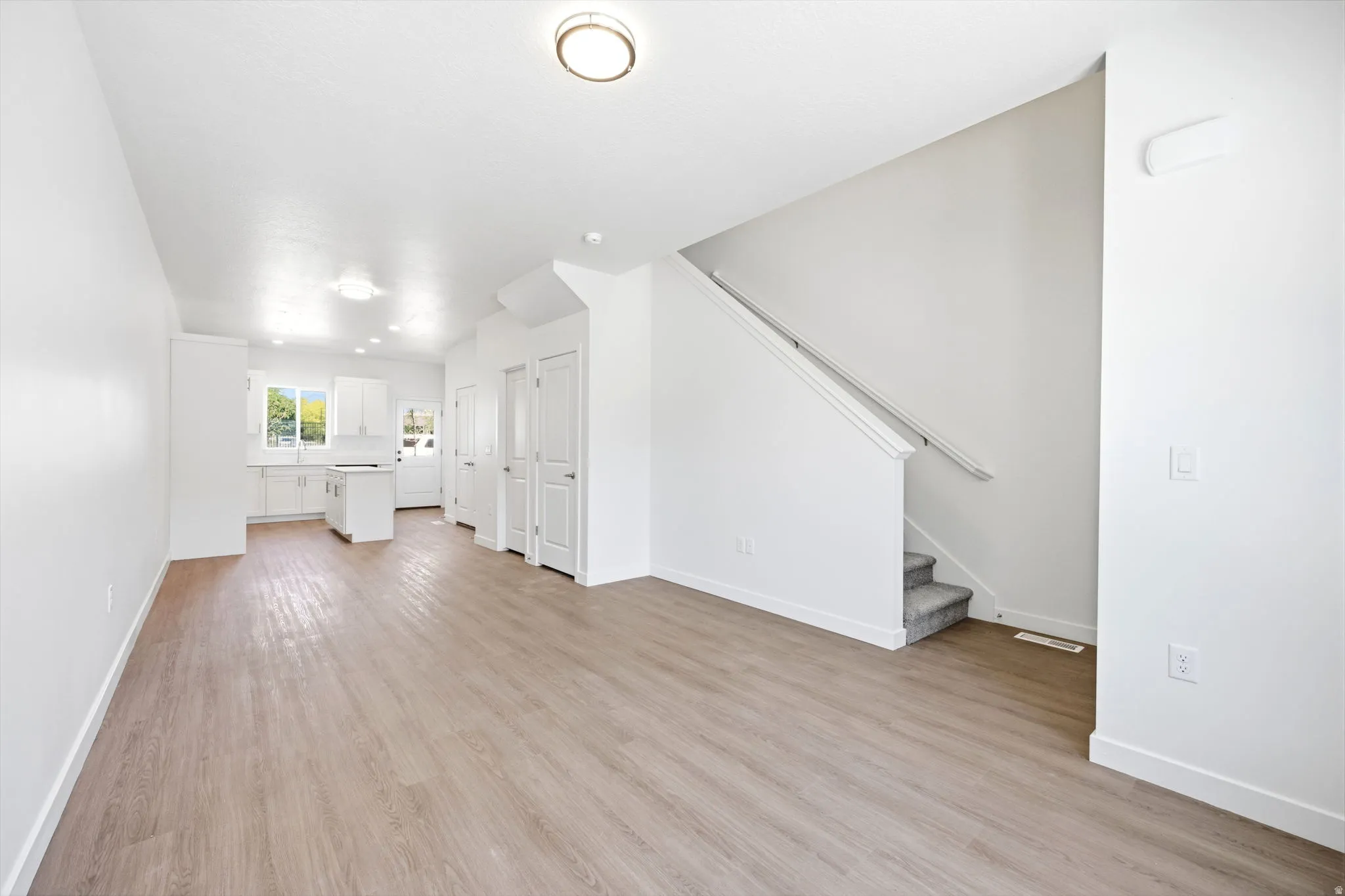 Spacious interior featuring wood-finish flooring, white walls, and a recessed ceiling light