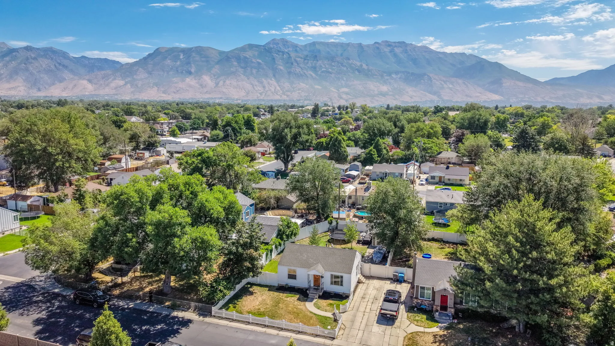 Aerial perspective showcasing a residential neighborhood with established trees, paved streets, and a prominent mountain range in the background