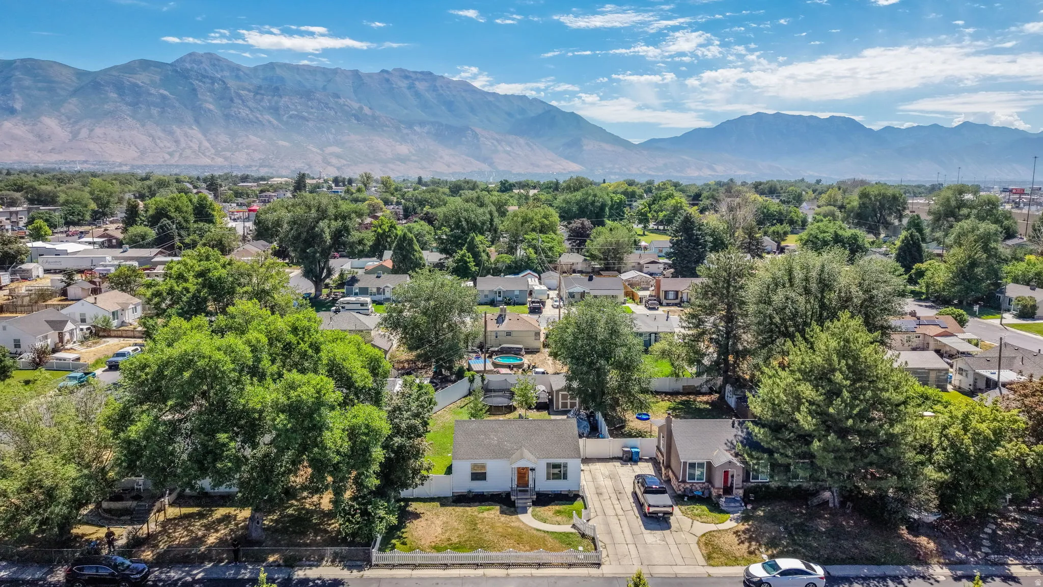 Expansive aerial view showcasing a neighborhood with mature trees and mountain scenery