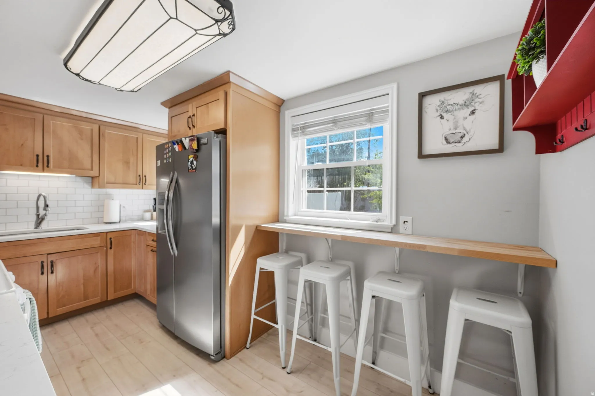 Kitchen with wood-finish flooring, light wood cabinetry, and white subway tile backsplash