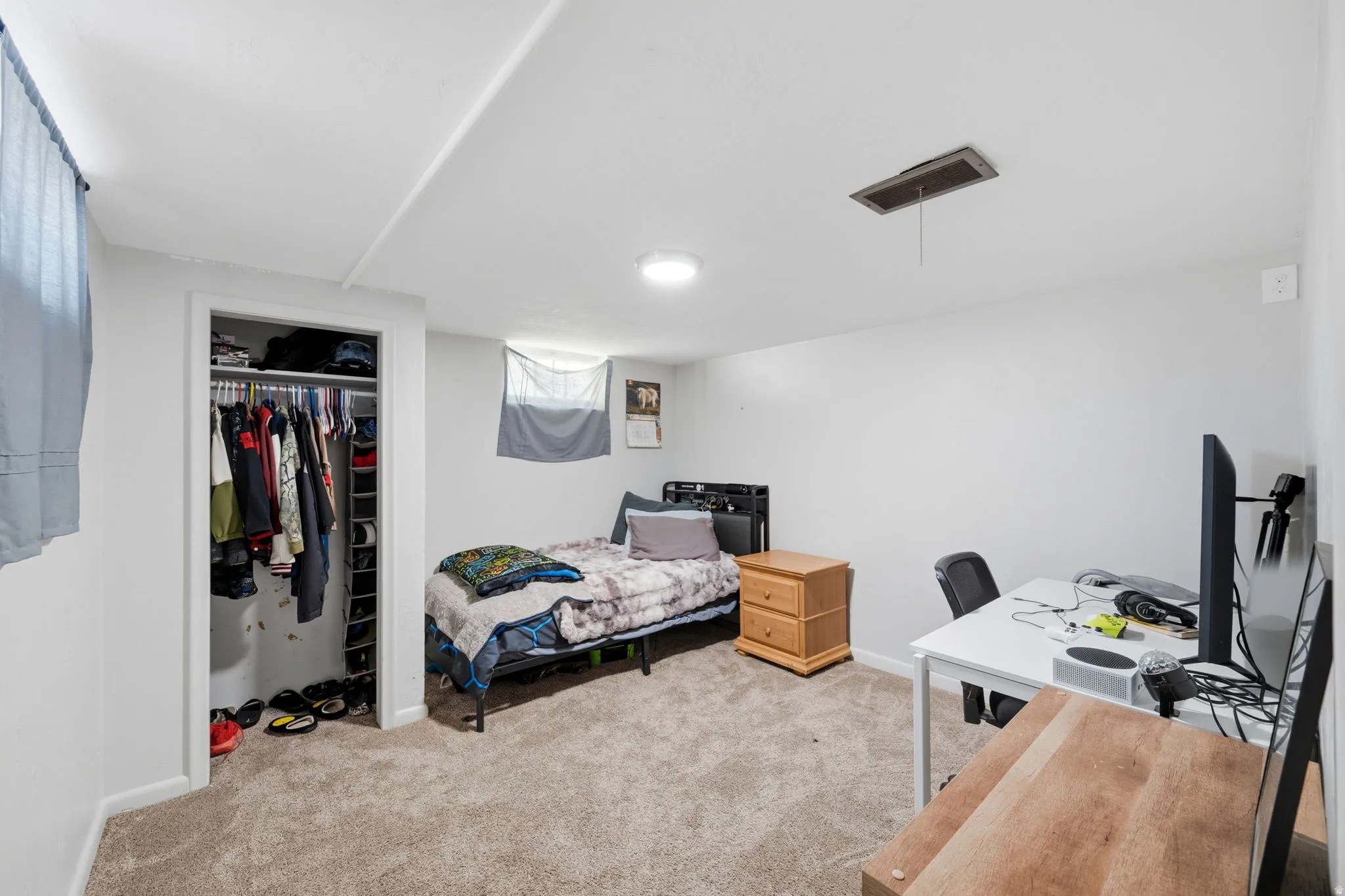 Carpeted room featuring a built-in closet with shelving, white painted walls, and a flush-mount ceiling light