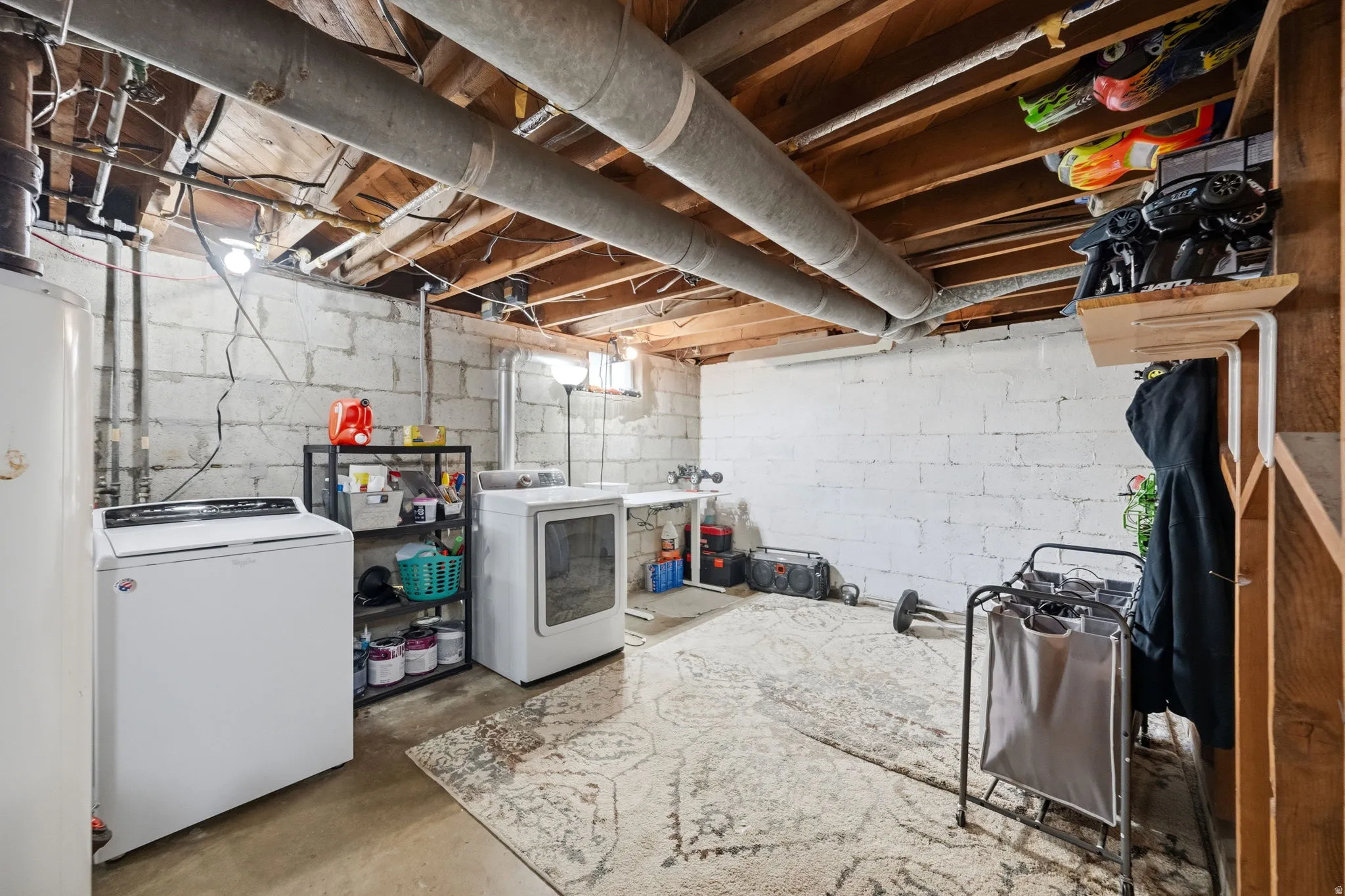 Basement space featuring exposed ceiling joists, concrete block walls, and concrete flooring
