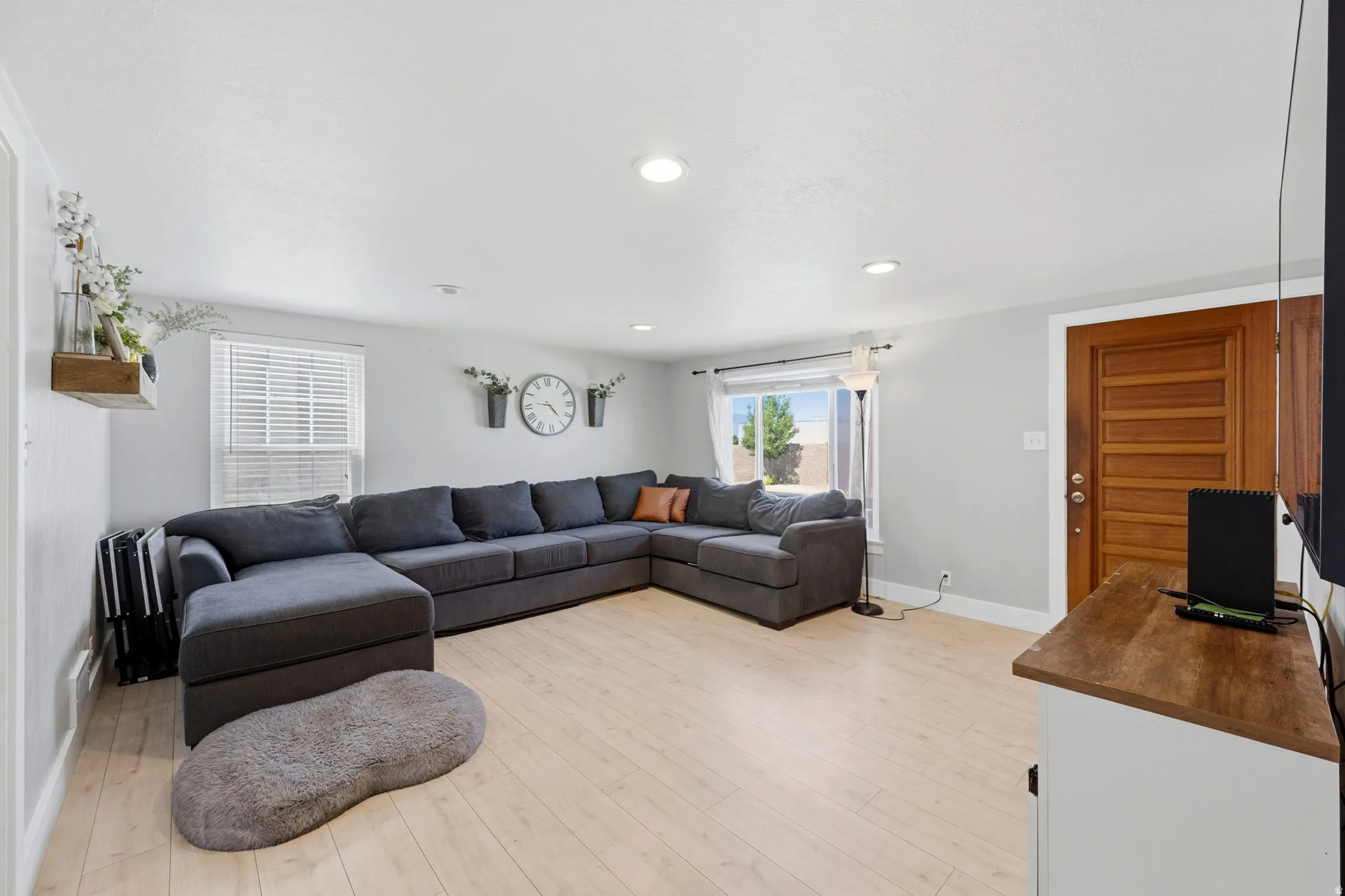 Bright living area featuring light wood-finish flooring, recessed lighting, and crisp white baseboards