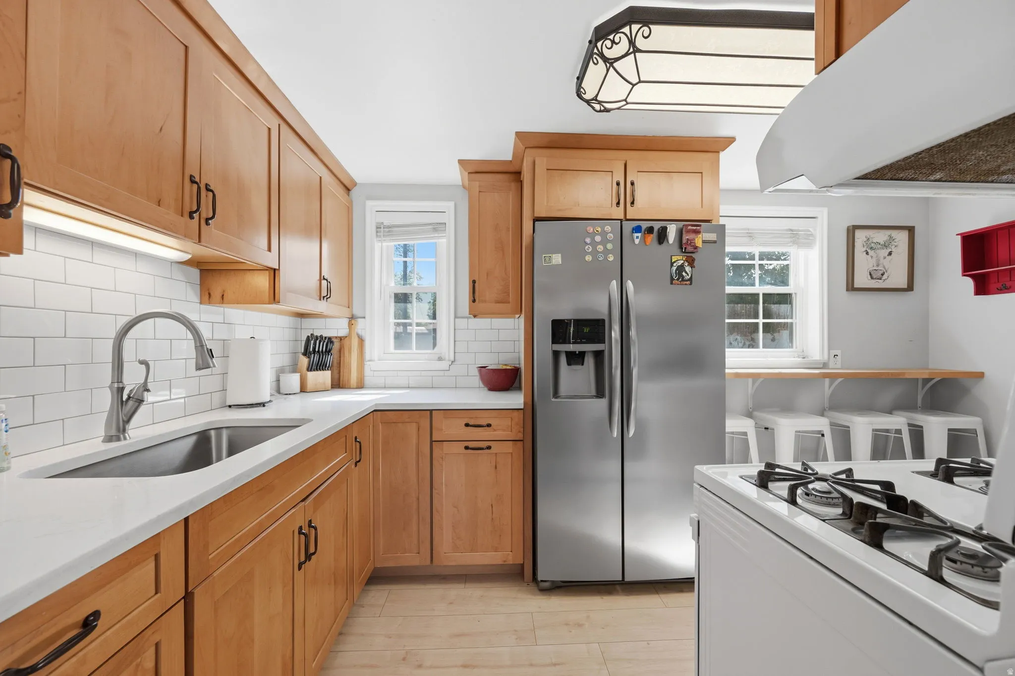 Kitchen featuring light wood cabinetry, white subway tile backsplash, and light-toned countertops