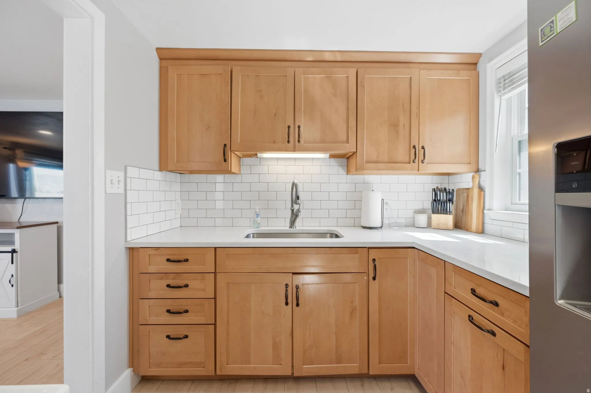 Kitchen featuring natural wood-finish cabinetry, white subway tile backsplash, and light-toned countertops