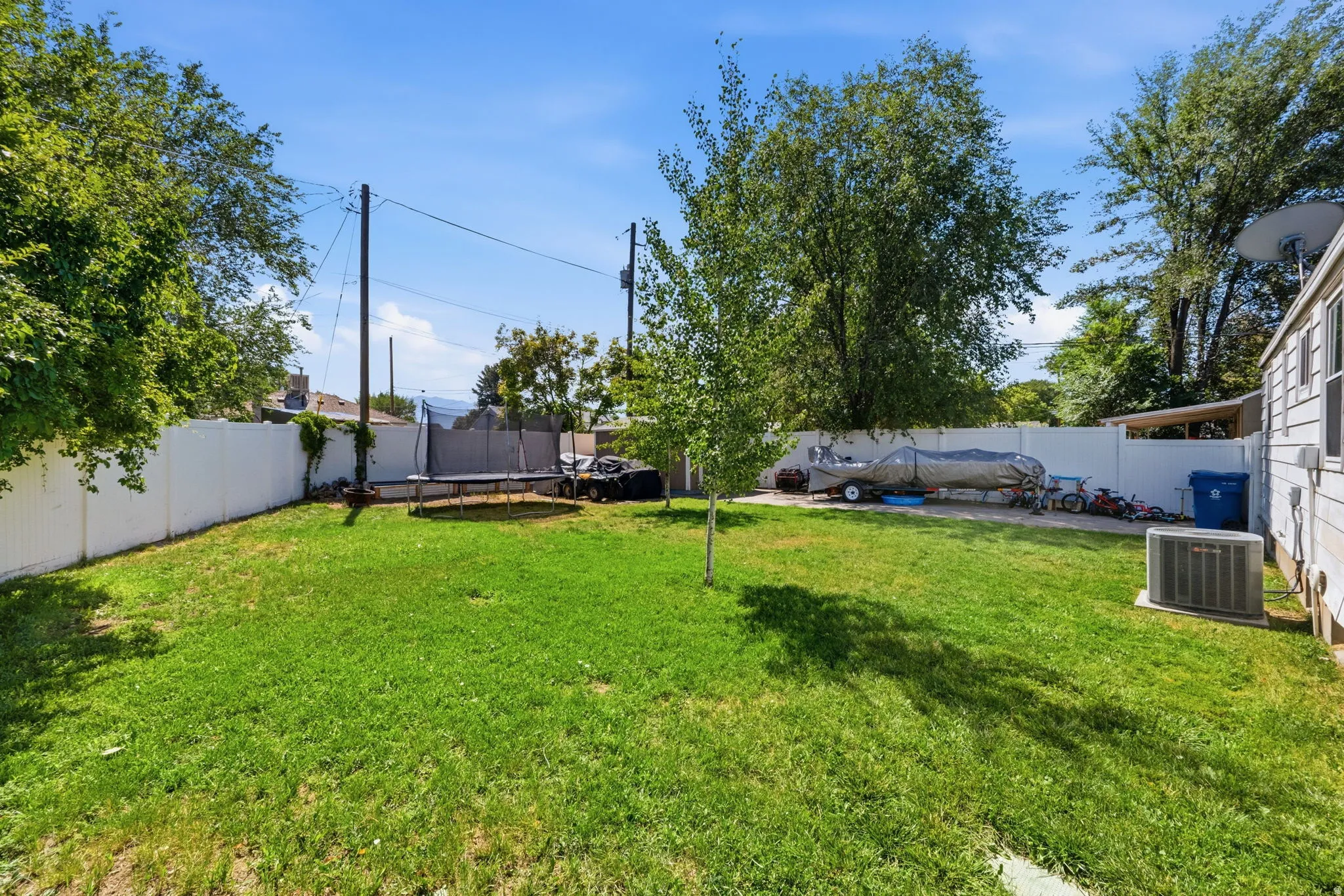 Expansive backyard featuring a lush green lawn, full privacy fencing, and mature trees providing natural shade