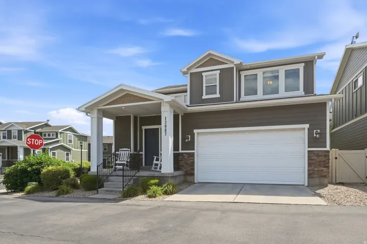 Modern two-story residence featuring a covered front porch with white columns, a neutral siding exterior, and stone accents