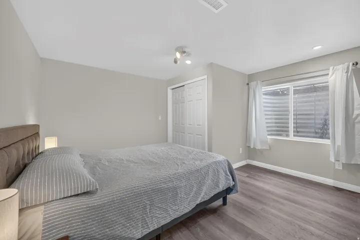 Room featuring light gray walls, wood-finish flooring, a bi-fold closet door, a window with white blinds, and recessed lighting