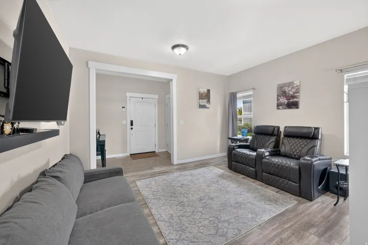 Open-concept living space featuring wood-finish flooring, neutral wall tones, white trim, and a white paneled entry door