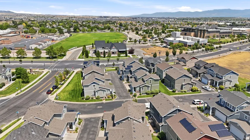 Aerial perspective showcasing a residential area with varied home exteriors, a manicured green space, and a backdrop of distant mountains