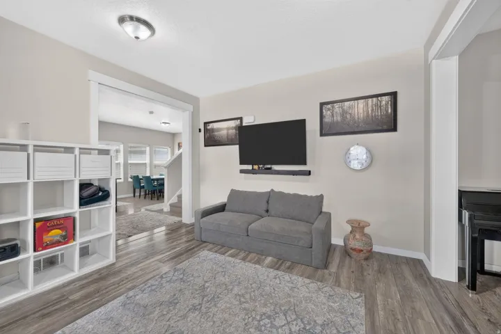Living area featuring wood-finish flooring, a neutral color palette, and a wide entryway