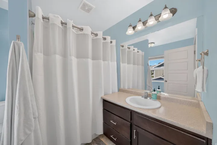 Bathroom featuring a dark wood-finish vanity with a light countertop, a single basin sink, and a large wall-mounted mirror
