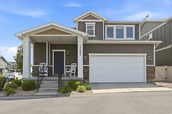 Contemporary two-story exterior featuring brown horizontal siding, a covered front porch with white columns, a dark front door, and a two-car garage with a white door