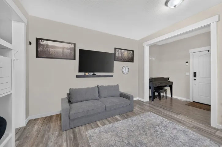 Spacious living area featuring wood-finish flooring, light-toned walls, and a wide entryway