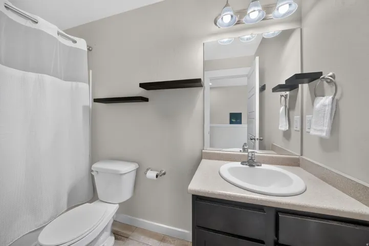 Bathroom featuring a single vanity with an integrated sink, dark wood-finish cabinetry, and a neutral countertop