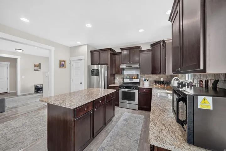 Kitchen featuring dark wood cabinetry, light-toned granite countertops, and stainless steel appliances