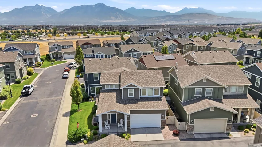 Residential neighborhood featuring a paved street and sidewalks, homes with neutral-toned siding, and a mountain backdrop