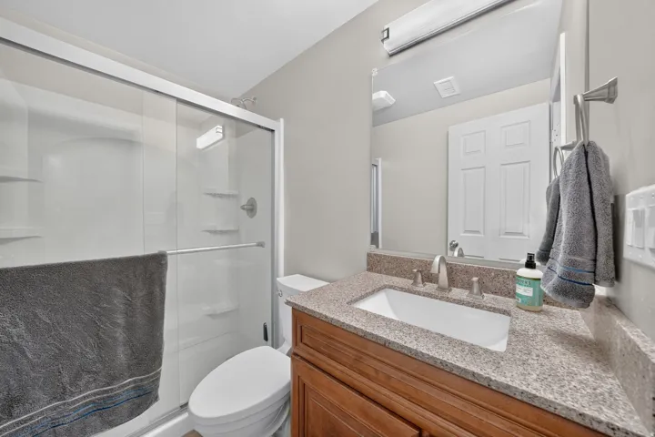 Bathroom featuring a wood-finish vanity with a built-in sink, stone-finish countertop, and brushed nickel fixtures