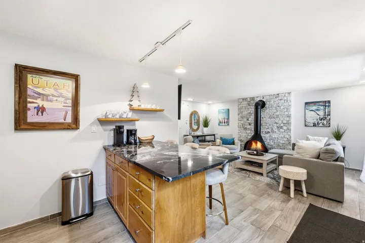 Open-concept living area featuring wood-finish flooring, a stone-accented wall, and a freestanding black fireplace