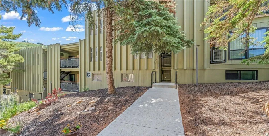 Multi-level residential building featuring a textured exterior facade and multiple balconies with metal railings