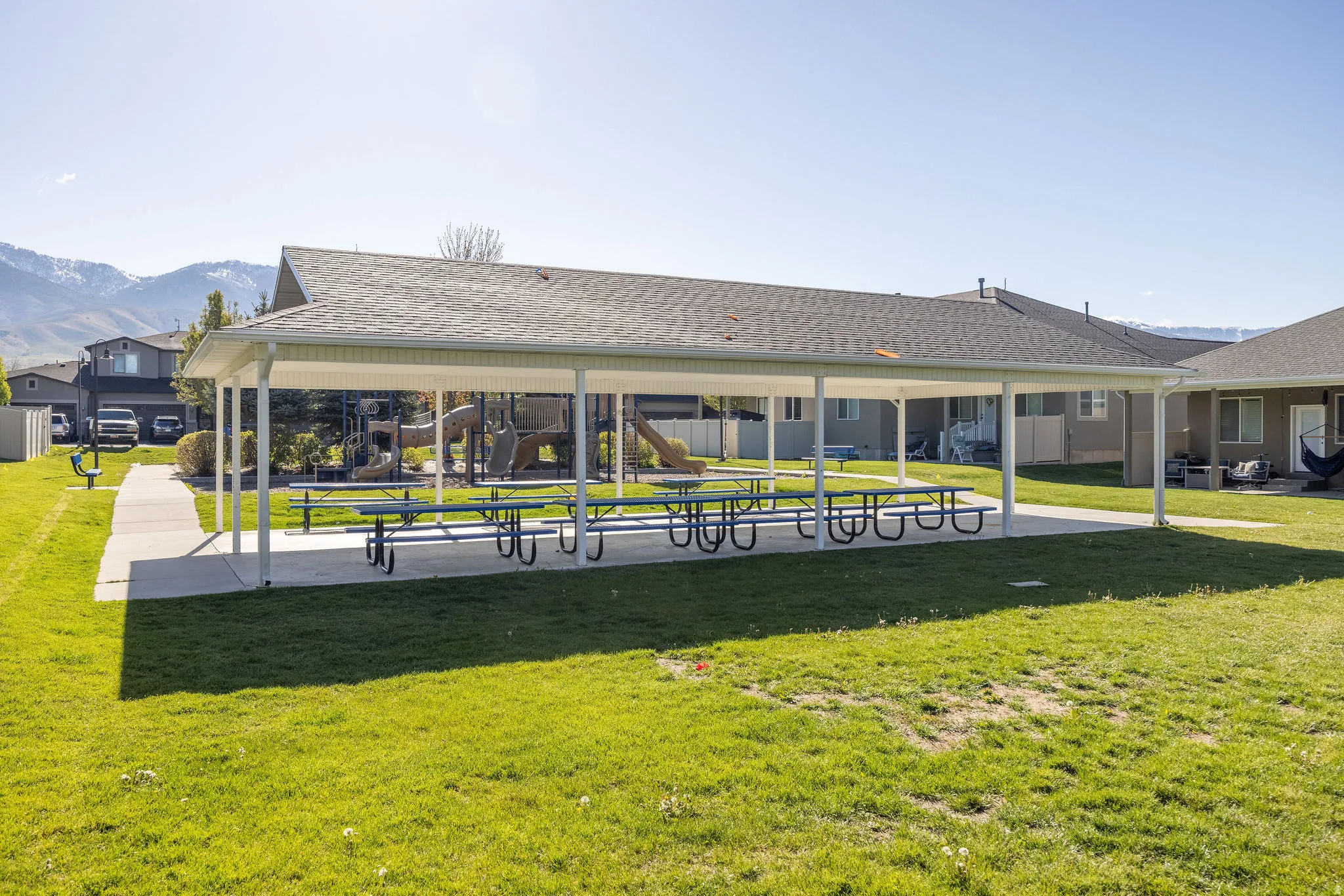 Covered outdoor pavilion with multiple picnic tables, a playground structure