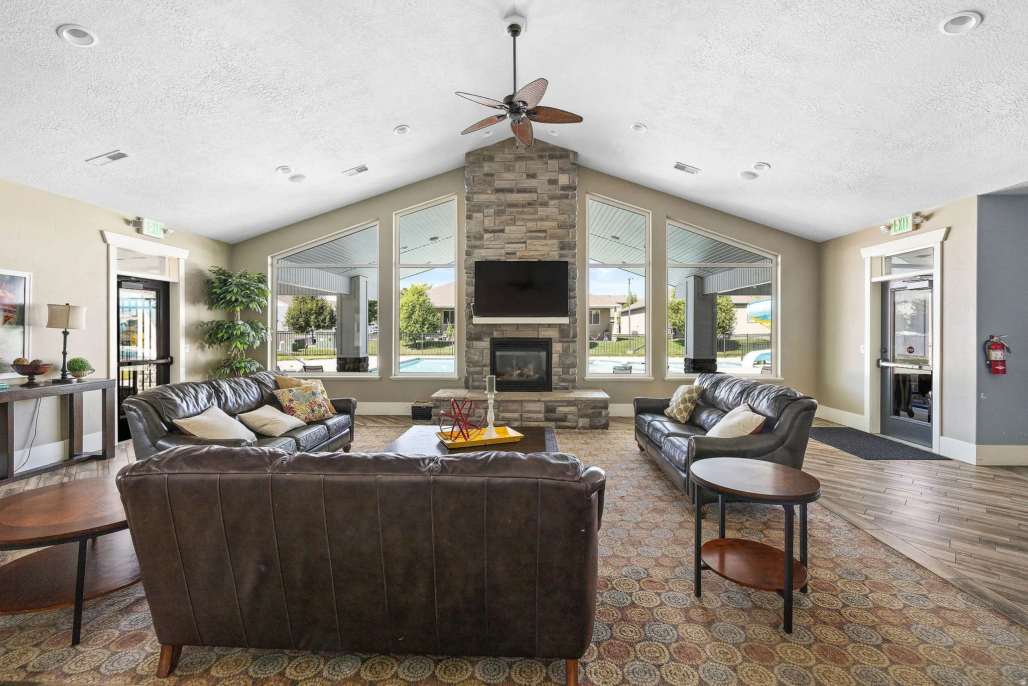 Spacious common area featuring a stone-clad fireplace and large picture windows