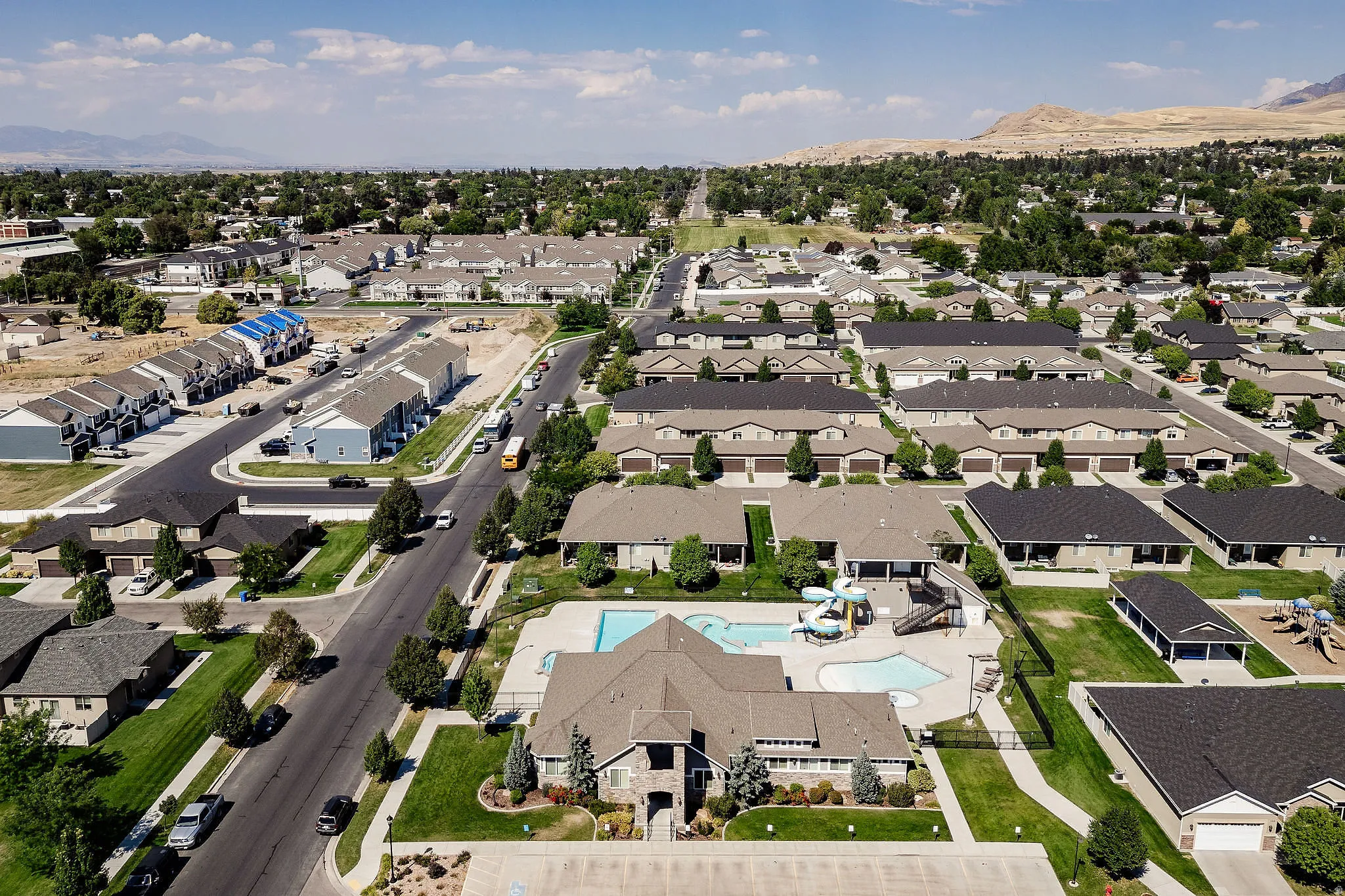 Community aerial showcasing residential properties, a central clubhouse, and a swimming pool