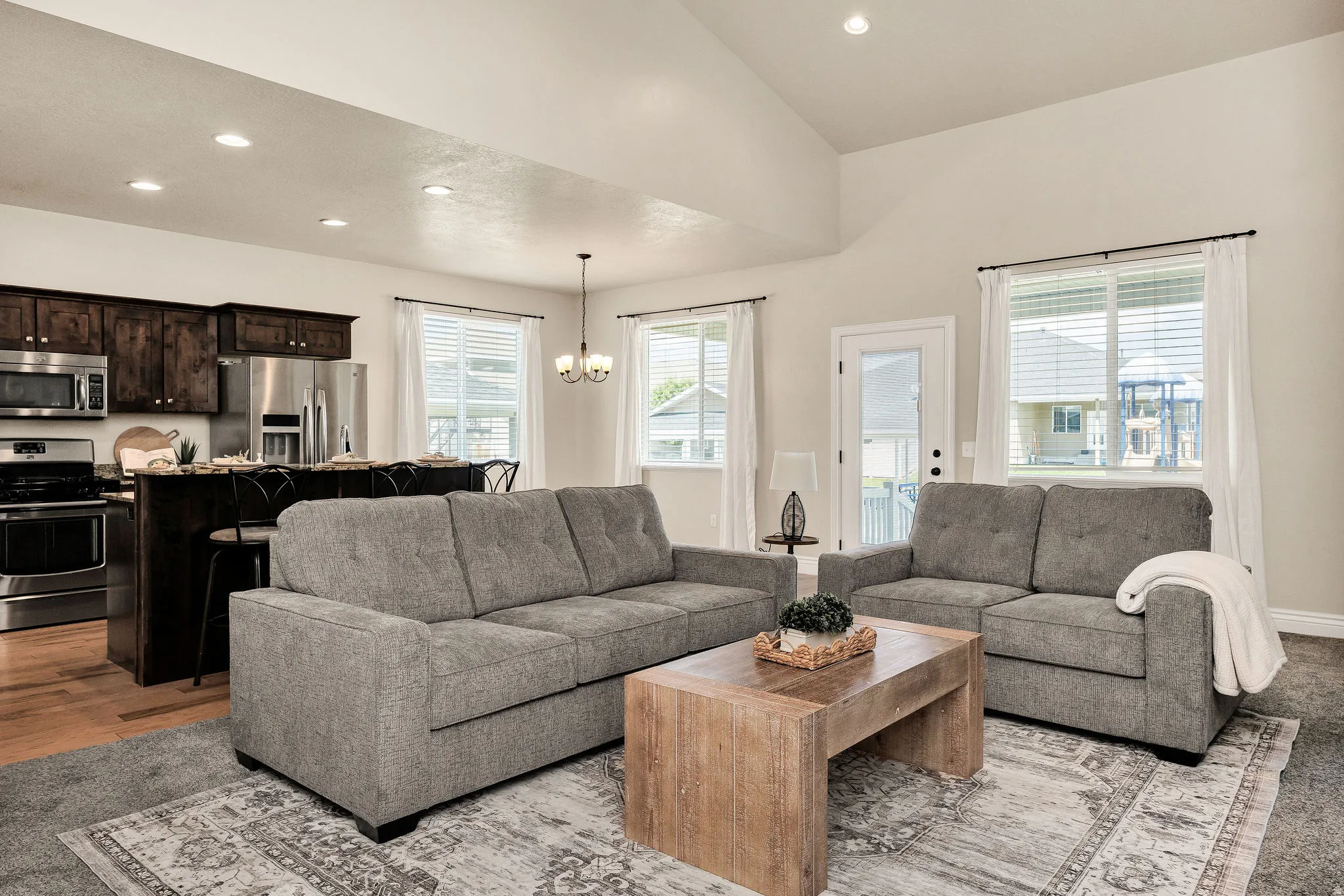 Open-concept living space featuring vaulted ceilings, recessed lighting, and large windows