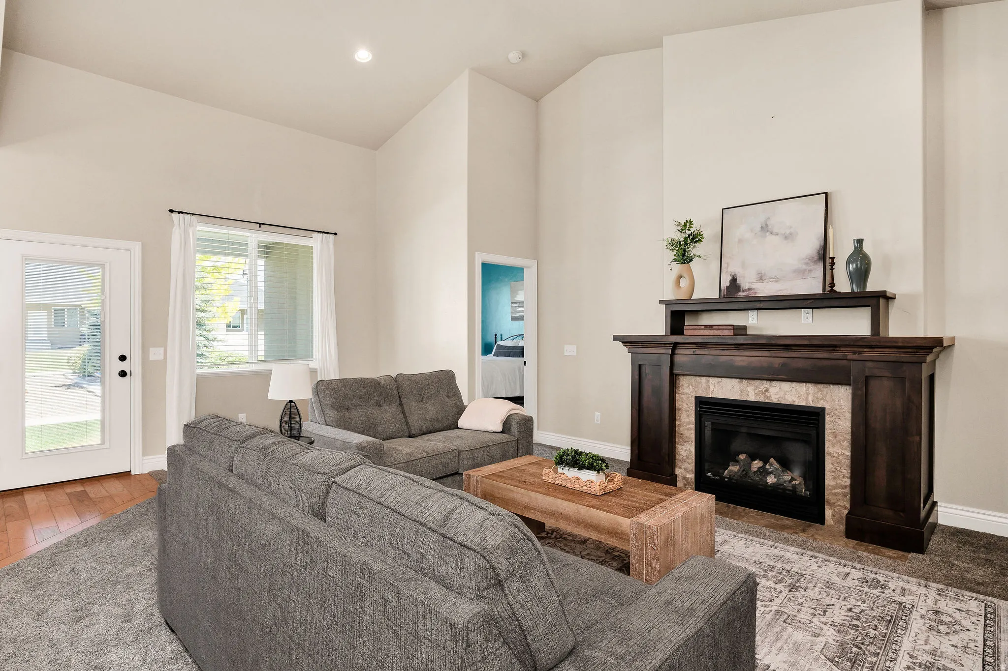 Vaulted ceiling living room featuring a gas fireplace with a dark wood mantel and stone surround
