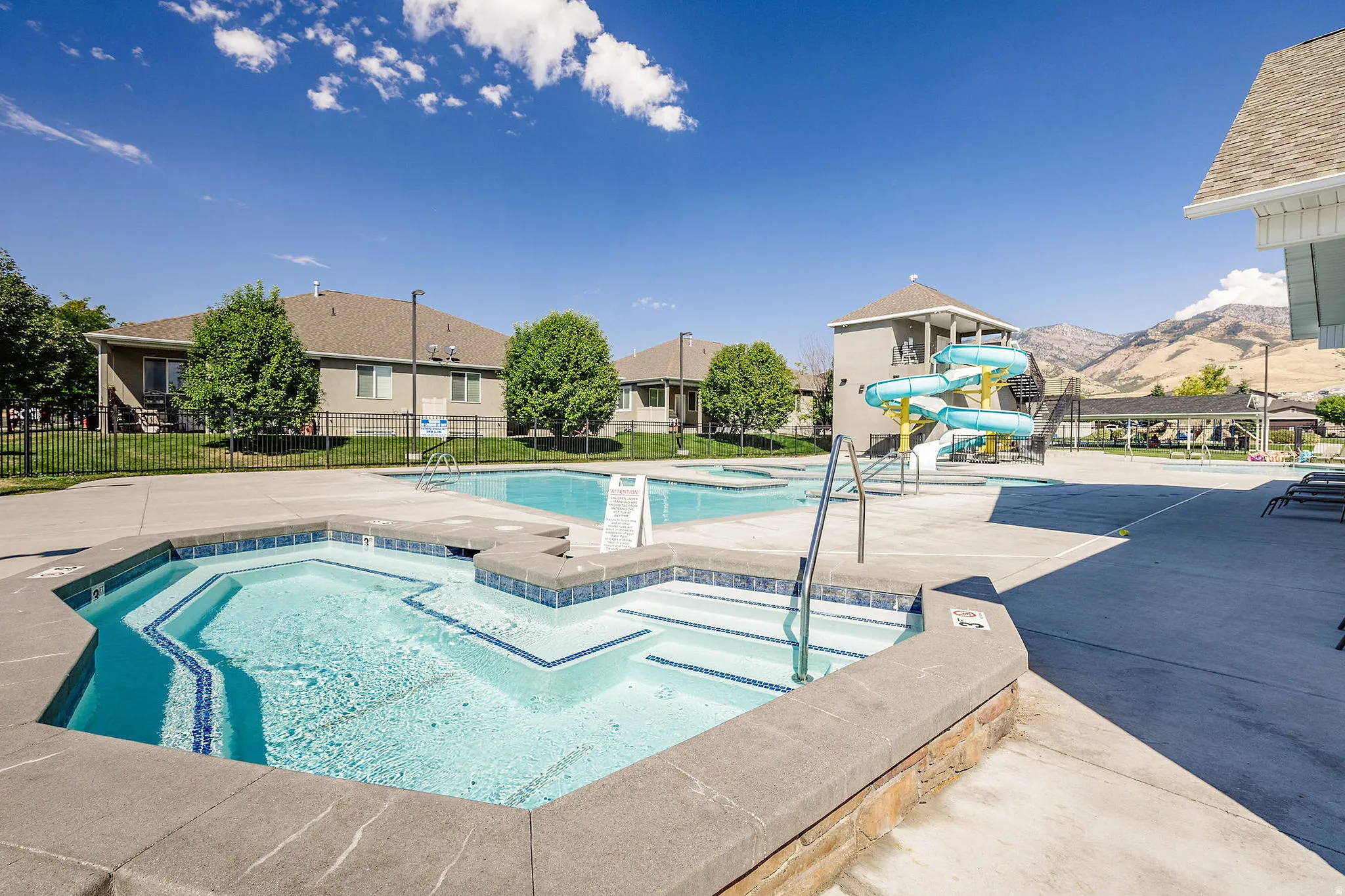 Community swimming pool featuring a hot tub, sun deck, and water slide