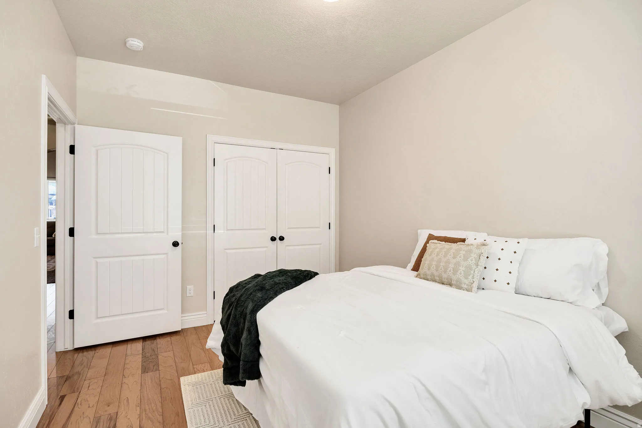 Bedroom featuring wood-finish flooring, white paneled doors, and light neutral wall tones