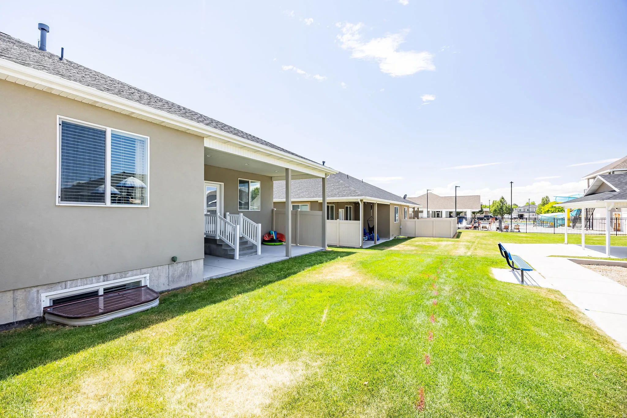 Rear exterior featuring a covered patio, stucco siding, and a basement window well