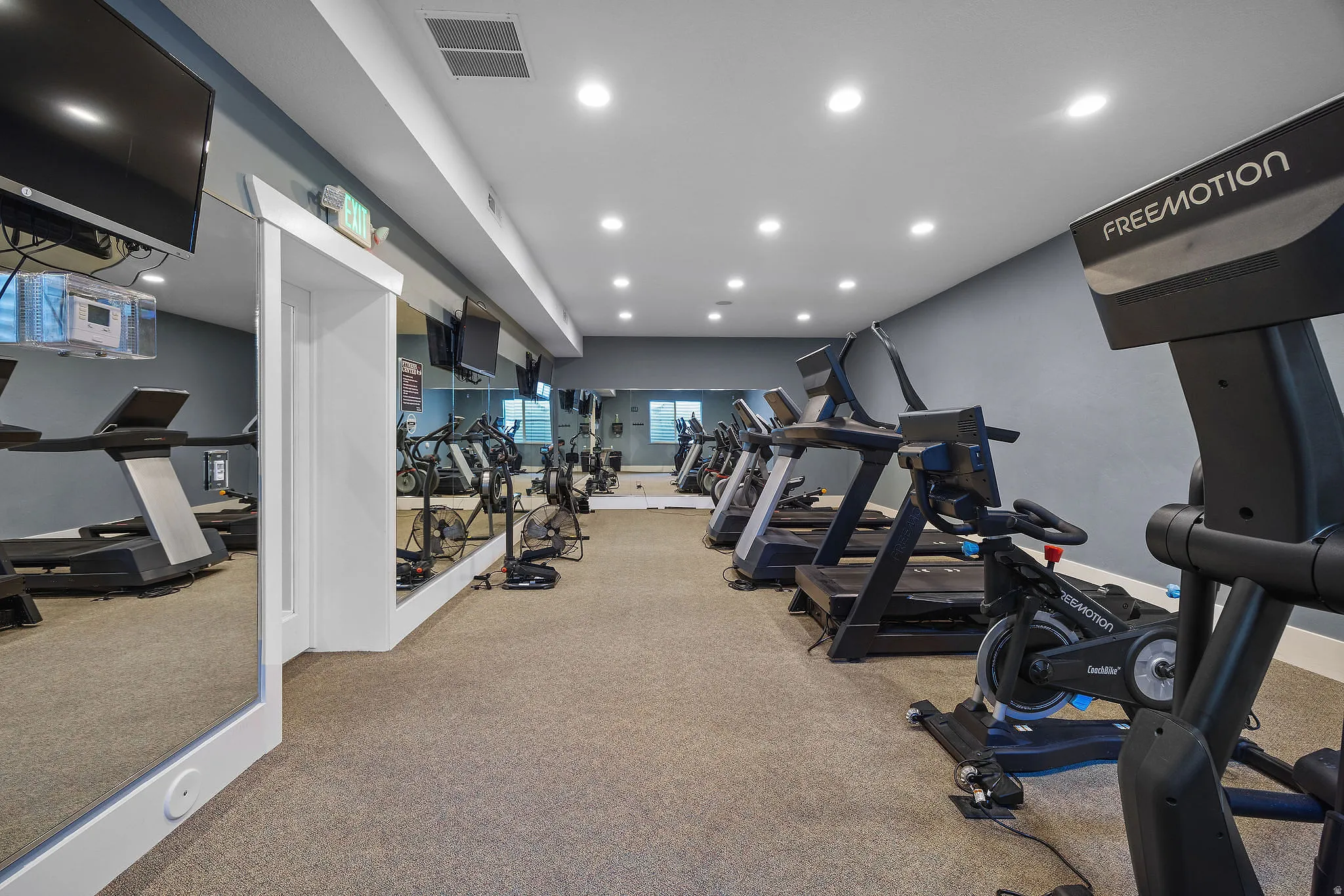 Fitness center featuring cardio equipment, wall-mounted televisions