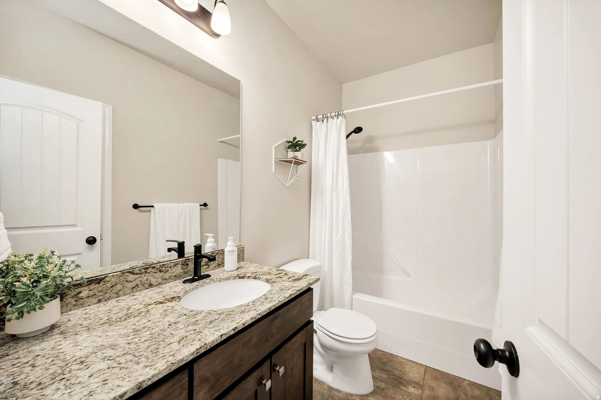 Bathroom featuring a spacious vanity with a light-toned granite countertop and an undermount sink