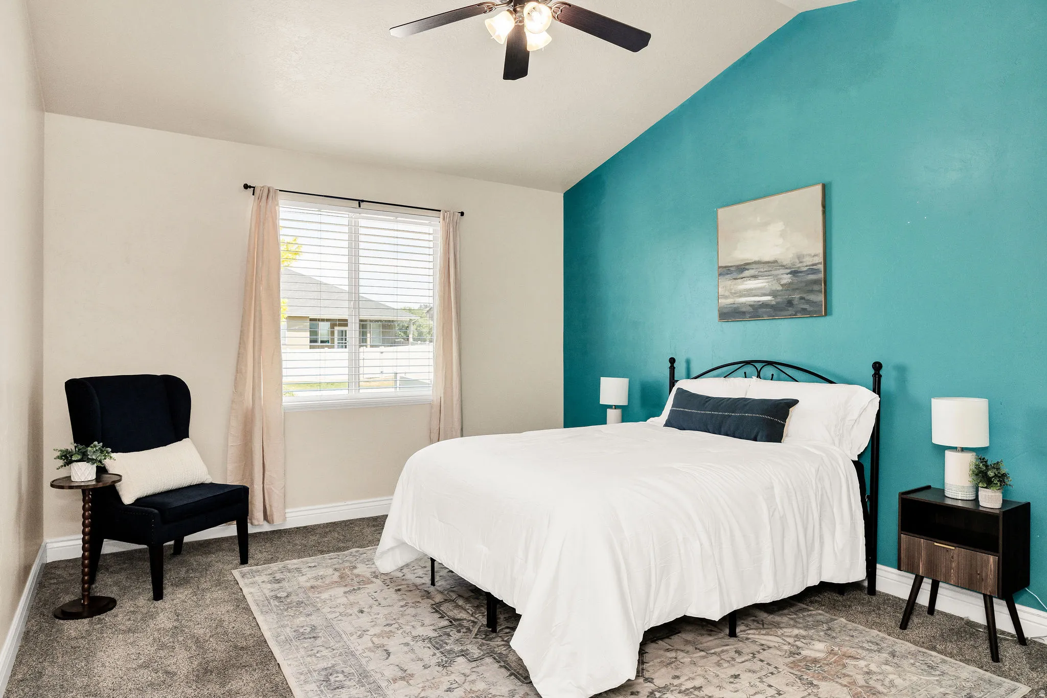 Vaulted ceiling primary bedroom with a vibrant accent wall, ceiling fan, and window with blinds