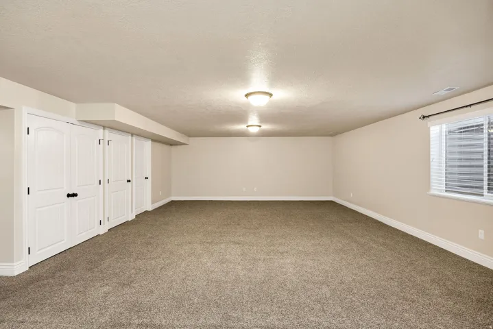 Spacious room featuring neutral carpeting, light-toned walls, and multiple white paneled bifold doors