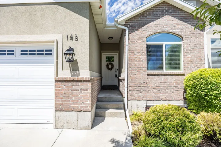 Exterior featuring a stucco finish, brick accents, and a white garage door with window inserts