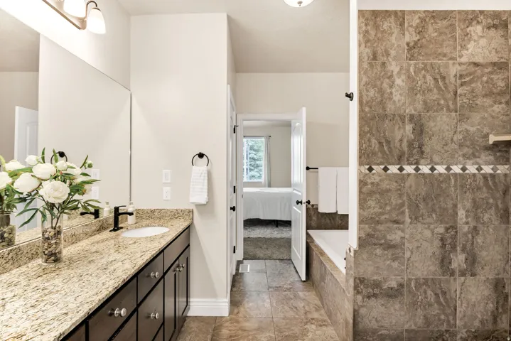 Primary bathroom featuring a double vanity with granite countertops, dark wood cabinetry