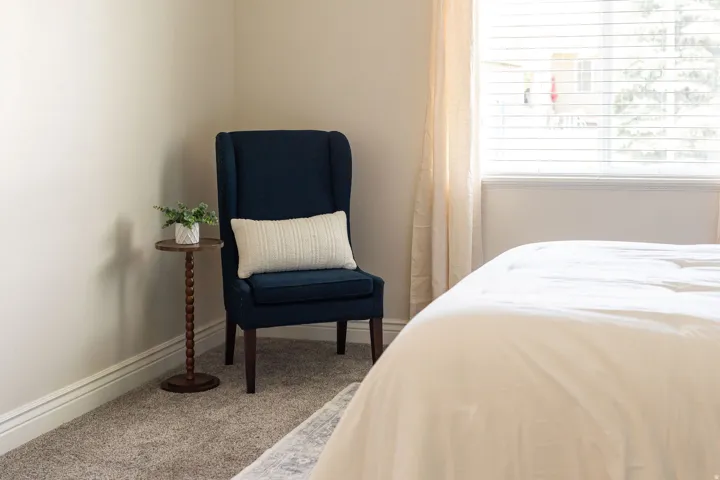 Neutral wall color, light-toned carpet flooring, white baseboards, and window with blinds and drapes