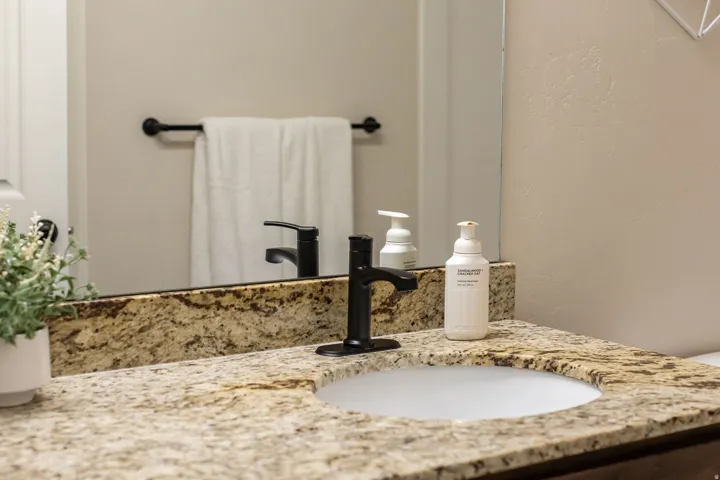 Primary bathroom vanity featuring a speckled granite countertop, and matte black faucet