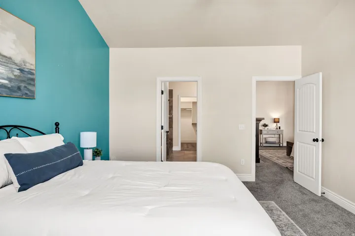 Primary bedroom featuring a vaulted ceiling and a distinct accent wall